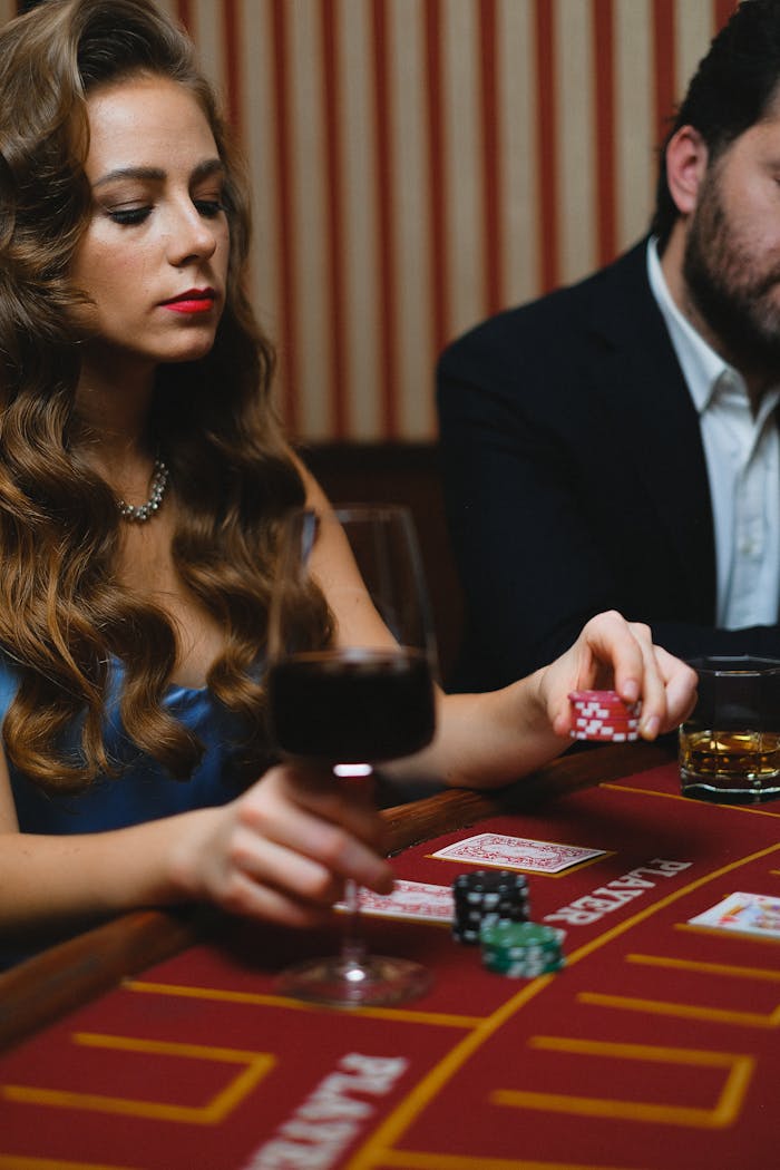 A glamorous woman playing poker at a casino table with poker chips and a glass of wine.